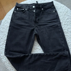Svarta jeansbyxor från Weekday - Snygga svarta jeansbyxor från Weekday med knappgylf och klassisk femficksdesign. Perfekta för en stilren look. Storlek 24/30 (låga i midjan)