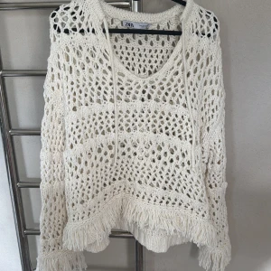 Vit stickad tröja från Zara - Säljer en vit stickad tröja från Zara med ett öppet mönster och fransdetaljer vid ärmslut och nederkant. Tröjan har långa ärmar och en avslappnad lock!