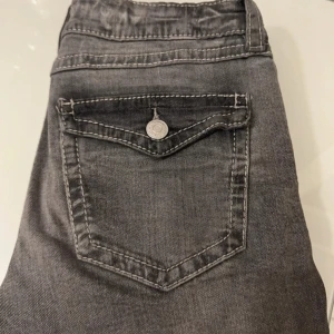 Grå jeans från Gina Tricot - Snygga grå jeans från Gina Tricot med klassisk femficksdesign och knappgylf. Perfekta för en avslappnad stil med en modern touch. Passar bra till både sneakers och kängor.