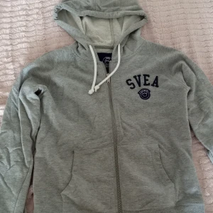 Grå hoodie från Svea - Grå hoodie från Svea med dragkedja och ficka på magen. Storlek 150 men är som XS. 