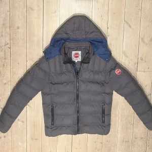 Grå pufferjacka från Colmar - Säljer en snygg grå pufferjacka från Colmar. Denna modell är väldigt eftertraktad och trendig. Den har lagats i ena armhålan då det var ett hål där. Detta är dock inget som syns utifrån och knappt inifrån. Skick: 9/10    Nypris: ca 6000kr