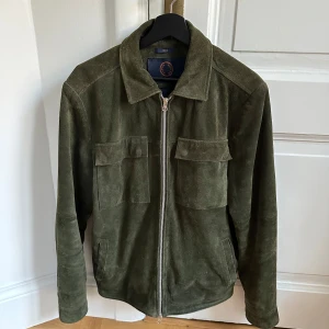 Grön mockajacka från Human Scales  - Grön mockajacka med dragkedja från Human Scales. Mycket bra skick, endast använd ett fåtal gånger. Storlek M.