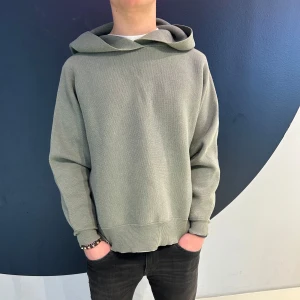 Grön hoodie med ribbade detaljer - Säljer en stilren grå hoodie med ribbade muddar och nederkant. Perfekt för en avslappnad look. Hoodien har en mjuk och bekväm passform.