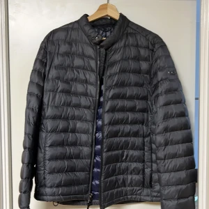 Michael Kors, Svart/Grå quiltad pufferjacka - Snygg svart quiltad pufferjacka med dragkedja och hög krage. Perfekt för kyliga dagar med sin stilrena design och bekväma passform. Jackan har långa ärmar och en diskret logga på ärmen.