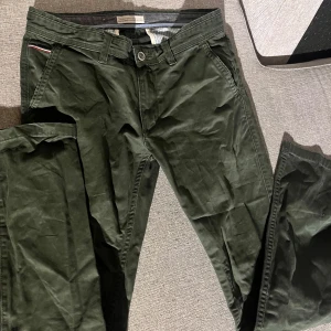 Gröna byxor från Lindbergh - Snygga gröna byxor från Lindbergh med normal passform. Byxorna har en klassisk design med knappar och dragkedja. Perfekta för en stilren look. Har legat i min byrå så därför är dem lite skrynkliga. W:32 L:34