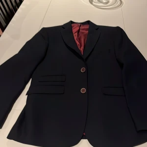 Mörkblå kavaj från Miroglio Lana - Elegant mörkblå kavaj från Miroglio Lana med en skräddarsydd passform. Kavajen har två knappar framtill och är tillverkad i en blandning av polyester och ull för en bekväm känsla. Perfekt för en stilren look.