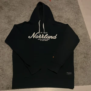 En snygg mörkblå hoodie, Norrland, SQRTB company - Säljer en snygg mörkblå hoodie från SQRTN Company med texten 'The Great Norrland' tryckt på framsidan. Hoodien har en justerbar dragsko i huvan och är perfekt för en avslappnad stil. Tröjan är lite missfärgad på luvan. Hör av er om ni har några frågor och priset är såklart inte hugget i sten