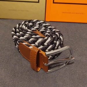 Flätat Bälte i Svart, Vit och Grå - Snyggt flätat bälte i svart, vit och grå. Helt nytt. Skick 10/10. 105 cm långt.