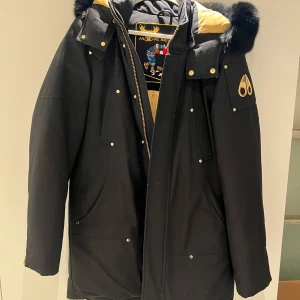 Svart parkajacka  - Säljer min pappas jacka                                     Moose knuckles jacka, äkta ( finns kvitto )   Endast använd fåtal gånger,                              nypris - 17 000kr  