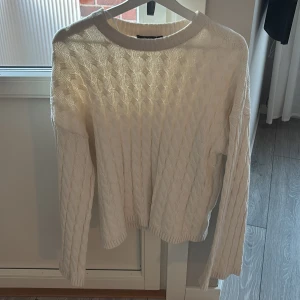 Vit stickad tröja - Säljer en  vit stickad tröja med kabelstickat mönster. Breda armar.