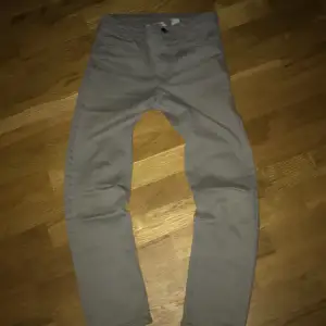 Säljer ett par grå slim fit byxor från H&M med justerbar midja. Perfekta för en stilren look och bekväma att bära. Passar för barn i åldern 10-11 år.