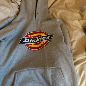 Grå hoodie från Dickies - Säljer en klassisk grå hoodie från Dickies med original loggan. Inga difekter utom att snöret är borta. Strl s men skulle säga att den är M
