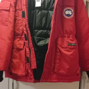 Röd dunjacka från Canada Goose - Säljer en röd dunjacka från Canada Goose med ikonisk logga på bröstet. Jackan har flera praktiska fickor och en dragkedja framtill. Perfekt för kalla vinterdagar med sitt varma dunfoder. jackan är äkta och har äktehetsbevis. storlek M men är lite stor I storleken så har man L så passar den också. fler bilder kan skickas och priset går att diskutera. Den finns I halmstad om man bor i närheten och vill kolla på den och testa den. pris 2000kr 