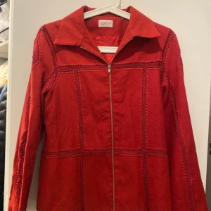 Röd jacka med dragkedja - Säljer en snygg röd jacka från Lizsport i bra skick. Jackan har en dragkedja framtill och långa ärmar. Den är perfekt för höst och vår med sitt stilrena utseende och bekväma passform. Passar både till vardags och lite finare tillfällen. 🌟