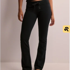 Svarta mjukisbyxor med knytband - Säljer ett par svarta mjukisbyxor i mycket bra skick. De är lågmidjade med ett praktiskt knytband i midjan för bästa passform. Byxorna har en bootcut-stil som ger en avslappnad look. Perfekta för mysiga dagar hemma eller en avslappnad dag ute. Prislapp kvar.