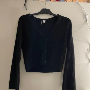 Svart ribbad kofta - Säljer en stilren svart ribbad kofta med knappar framtill. 
