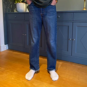 Blå Levi’s jeans Ribcage Straight Ankle - Snygga blå Levi's Ribcage Straight Ankle jeans med hög midja och rak passform. Perfekta för en avslappnad stil med en klassisk look. De har en traditionell femficksdesign och är tillverkade i slitstarkt denim.
