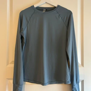 Grå/blå långärmad tröja från Only Play - Säljer en stilren grå långärmad tröja från Only Play. Perfekt för träning eller vardagsbruk. Tröjan har en enkel design med rund hals och tumhål vid ärmsluten för extra komfort.