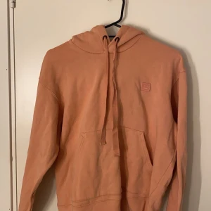 Rosa hoodie från Acne Studios - Säljer en superfin coral hoodie från Acne Studios. Den är i bra skick och har en klassisk passform med en känguruficka fram och en liten logga på bröstet. Perfekt för både höst och vår! 🧡Den är självklart riktig!