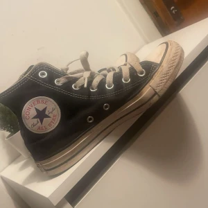 Svarta Converse All Star - Klassiska svarta Converse All Star i bra skick. De har den ikoniska vita sulan och snörning framtill. Perfekta för en avslappnad stil och passar till nästan allt. Lite slitna men fortfarande snygga och bekväma i storlek 37,5!🥰