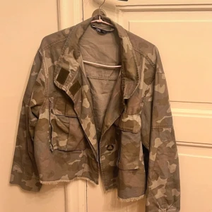 Camouflagejacka från Zara - Säljer en cool camouflagejacka från Zara i storlek XS. Jackan har en avslappnad stil med flera fickor och en skön passform. Perfekt för höst och vår, och den ger en grym look till vardagsoutfiten. Den är i bra skick och redo för nya äventyr!