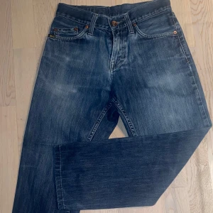 Blå jeansbyxor - Säljer ett par klassiska blå jeansbyxor med fem fickor och knappgylf. De har en rak passform och är perfekta för en avslappnad stil.