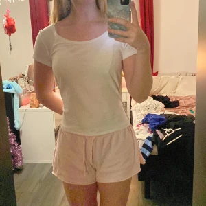 Vit kortärmad topp - Säljer en enkel och stilren vit kortärmad topp. Perfekt för en avslappnad look. Toppen har en rund halsringning och är gjord i ett mjukt material.