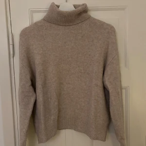 Beige stickad tröja - Mysig beige polotröja från H&M i en mjuk och varm ullblandning. Perfekt för kyliga dagar med sin ribbade polokrage och långa ärmar. En stilren och tidlös design som passar till det mesta. 🧥✨