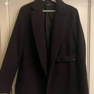 Svart kappa från Guess - Säljer en elegant svart kappa från Selected Femme. Den har en klassisk design med knappar och en stilren look. Perfekt för höst och vinter, och passar både till vardags och fest. Storlek M och i mycket bra skick.