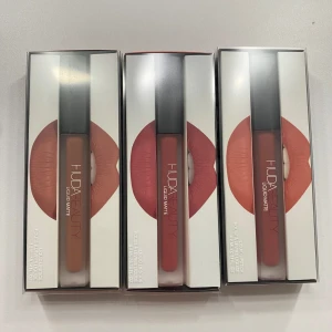 Huda Beauty Liquid Matte Lipstick Set - Säljer 3st nya oöppnade Huda Beauty Liquid Matte läppstift i nyanserna Trendsetter, Icon och Bombshell. Dessa flytande läppstift ger en matt finish och har lång hållbarhet. I tredje bilden kan man se hur färgerna sitter på läpparna. 🩷                                                                     150kr/styck.                                                                        Ny pris 329kr/styck  