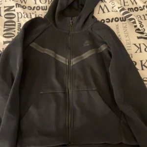 Svart hoodie från Nike - Säljer nu min älskade Nike tech tröja pga ingen användning längre , den är dock jätte fin och storleken är lite oklar men antar att det är XL i barn storlek ungefär 164/170 vilken innebär ungefär Xs den har passat på mig som har xs. 
