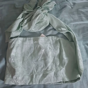 Ljusgrön tubtopp från Bik Bok - Säljer en superfin ljusgrön tubtopp från Bik Bok i storlek m, men funkar även för s. Toppen är i ett glansigt material med ett subtilt blommönster. Den har en smockad baksida för bättre passform och en stor knytrosett framtill så man kan stila den hur man vill! Aldrig använd, i nyskick med prislapp kvar😊😊💚