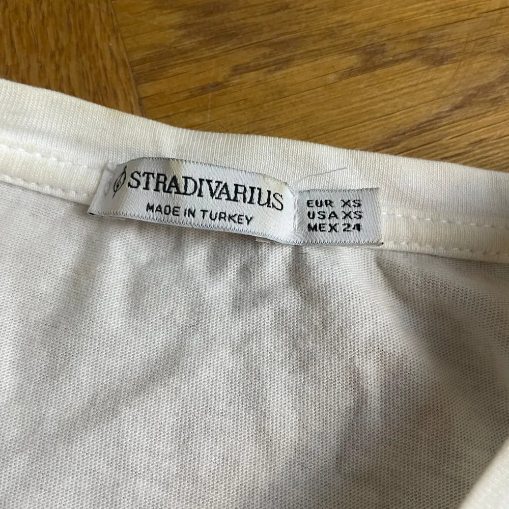 Säljer en vit t-shirt från Stradivarius i storlek XS. T-shirten har ett tryck på framsidan med texten 'TREND Alert' och olika blå och silver detaljer. Perfekt för en avslappnad och trendig look. Använd men i bra skick.. T-shirts.