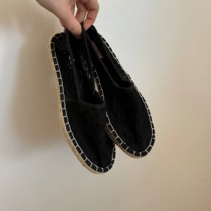 Svarta spetsiga espadrillos från Hunkemöller - Säljer ett par svarta espadrillos från Hunkemöller. De är gjorda av spets och har en snygg, flätad sula. Perfekta för sommaren och passar till både vardag och fest. De är i nytt skick och har en bekväm passform.