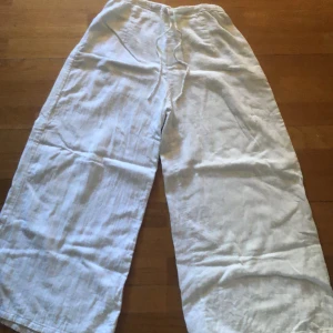 Vita linnebyxor från Le temps d'un été - Säljer ett par vita linnebyxor från Le temps d'un été. De är superbekväma och perfekta för sommaren. Byxorna har en loose fit med breda ben. denhar en liten fläck på ena benet. Perfekta för en avslappnad dag på stranden eller en somrig utflykt! 🌞där snörerna sitter är det också lite slitet.
