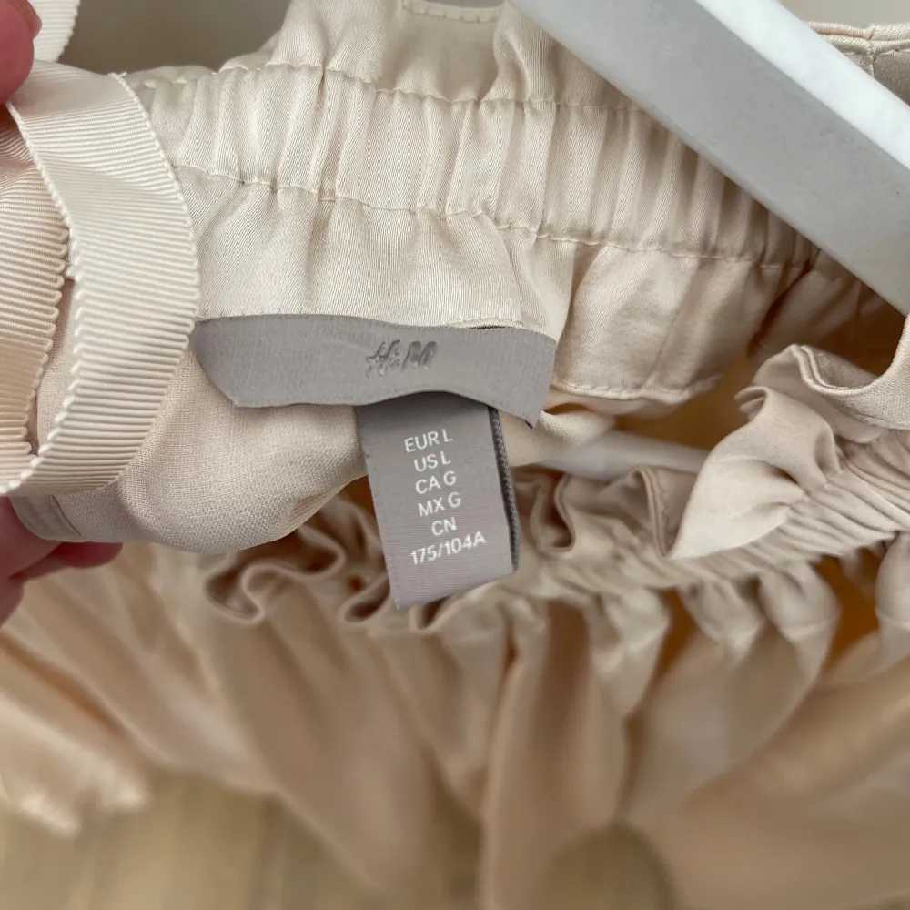 Beige blus från H&M med fina detaljer. Rosett i nacken som man kan knyta själv. Använd fåtal gånger. Storlek L. Blusar.