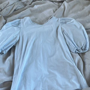 Ljusblå topp - Söt ljusblå topp/ t-shirt med puffiga armar. Säljer pga ingen användning. Bra kvalitet, använt typ 2 ggr. Passar till det mesta