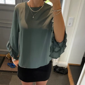 Grön trekvartsärmad volangblus  - Volangblus från Ginatricot i storlek 36. Fint skick. Använd gärna köp nu!