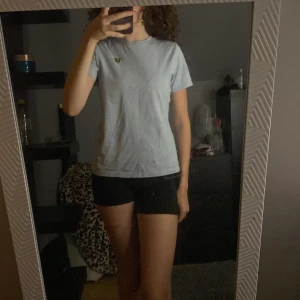 Ljusblå t-shirt från Lyle & Scott - Säljer en ljusblå t-shirt från Lyle & Scott. Den är i bra skick och har en liten gul logga på bröstet. T-shirten är gjord av bomull och är väldigt bekväm att ha på sig. Köp den nu eller ge ett bud! 💙