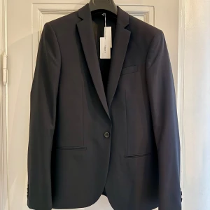 *Oanvänd* Filippa K M. Christian Cool Wool Jacket Dark Navy - Oanvänd Filippa K M. Christian Cool Wool Jacket Dark Navy (Nypris: 3000 kr)  • Enknäppt kavaj från Filippa K. • Material: 100% ull • Smal passform  Två infällda fickor i sidorna, en bröstficka samt tre innerfickor.  Skickas ej. Hämtas på Kungsholmen.