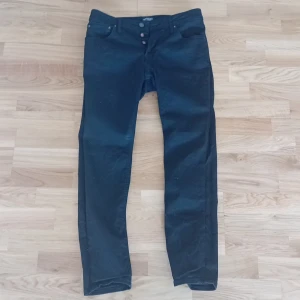 Svarta jeansbyxor - Säljer ett par svarta jeansbyxor i bra skick. De har en klassisk design med knappar i midjan och en smal passform. Perfekta för både vardag och fest!