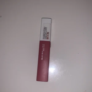 Super Stay Matte Ink läppstift från Maybelline - Säljer ett Super Stay Matte Ink läppstift från Maybelline. Färgen är en snygg röd nyans som håller länge och ger en matt finish. Perfekt för en kväll ute eller när du vill ha en hållbar look hela dagen. Läppstiftet har en praktisk applikator som gör det enkelt att applicera.