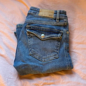 Blå jeansbyxor från 157 - Säljer ett par snygga blå jeansbyxor från lager 157. De är i storlek xxs  och har en klassisk femficksdesign med knappar och dragkedja. Byxorna är i bra skick och perfekta för vardagsbruk. Passar till alla tillfällen och är ett måste i garderoben! priset kan diskuteras 