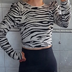 Zebramönstrad tröja, stickad tröja med knytdetalj strl S  - Säljer en supercool zebramönstrad tröja. Den är svart och vit med långa ärmar och en croppad passform. Tröjan har puffiga ärmar och ett knytband i midjan som ger en snygg detalj. Perfekt för höst och vår! 🖤🤍
