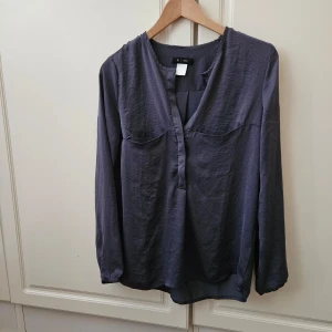 Mörkgrå blus från La Redoute - Använd 2 ggr Säljer en elegant mörkgrå blus från La Redoute. Blusen har en v-ringad hals och långa ärmar med knappar vid ärmsluten. Materialet är mjukt och bekvämt, perfekt för både vardag och fest. Köp direkt eller ge prisförslag 💛