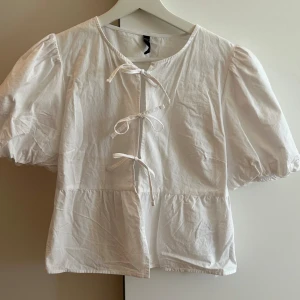 knytblus med puffärmar vit - Super gullig vit knytblus, kommer tyvärr inte till användning. Endast använd 1 gång så i nytt och fint skick. Är storlek m men passar xs/s också.  