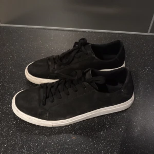 Svarta sneakers med vit sula - Snygga svarta sneakers med vit sula och snörning. Perfekta för en avslappnad stil. Sparsamt använda. Tvättar såklart innan jag skickar dem. 