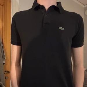 Lacoste piké  - En Lacoste piké i storlek 176 cm/S. Den har en bra passform och killen på bilden är 182 cm lång. Tröjan är i bra skick och om du undrar något så är det bara att höra av sig👍