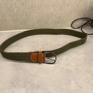 Grönt flätat bälte med bruna detaljer - Snyggt grönt flätat bälte med bruna läderdetaljer och svart spänne. Det är en väldigt fin färg som sticker ut lite i outfiten men ändå passar till allt älskar verkligen denna färg. Använd 1-3 gånger max skicket är som nytt. Du kan välja en valfri färg och får båda skärpen för 300kr.