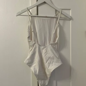 Weekday Vit baddräkt - Weekday ”Venus Mesh Swimsuit” vit baddräkt med djup rygg och reglerbara axelband. I dubbelt tyg, så är inte genomskinlig. Lite använd men har mycket kvar att ge! Väldigt smickrande och snygg. Har fått någon liten missfärgning på ryggen (se bild), som säkert går bort med blekmedel